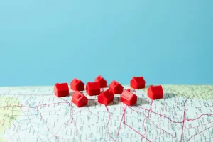 Miniatures de maisons rouges posées sur une carte illustrant la tension du marché locatif par ville